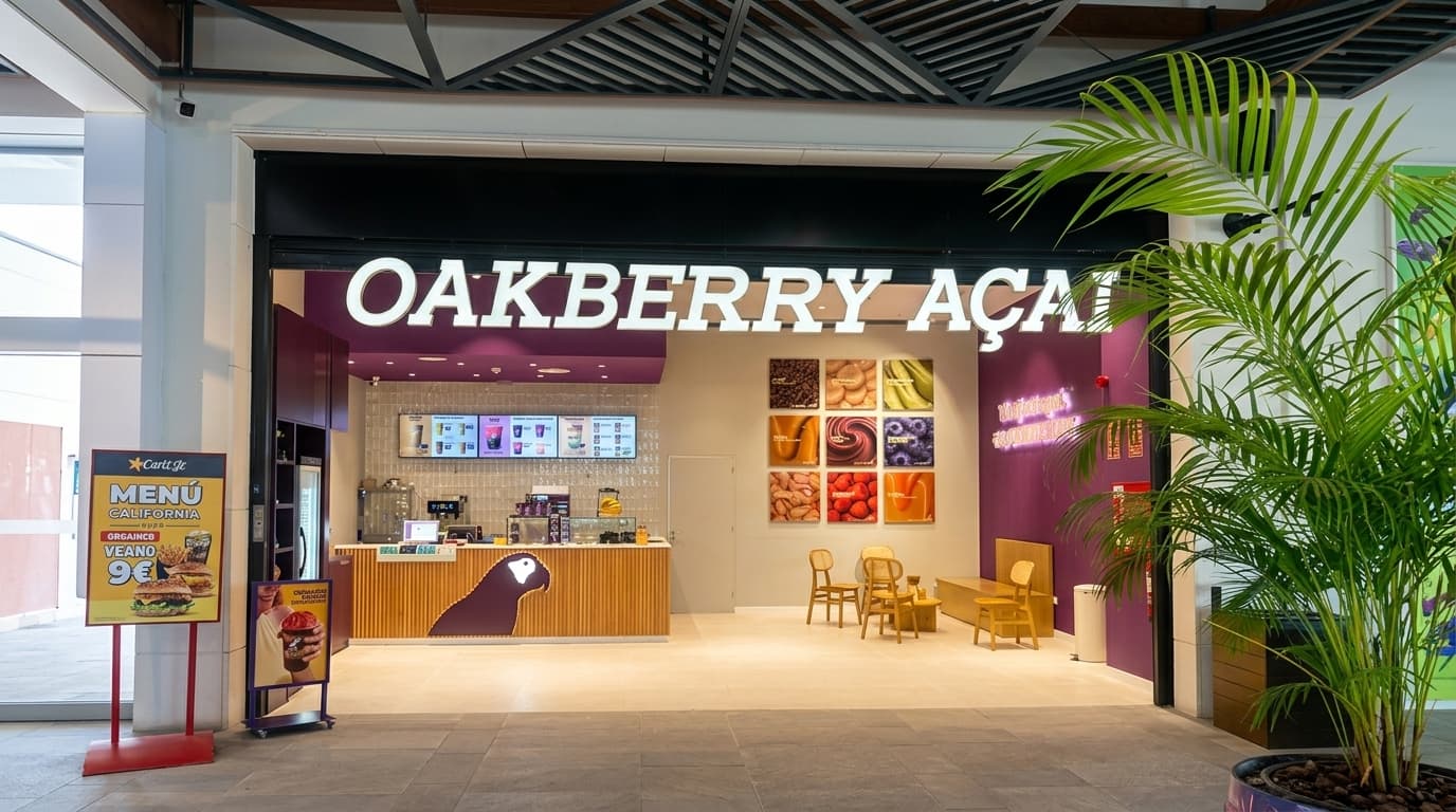 Fachada de tienda Oakberry Açaí reformada por Dunamis, con rótulo iluminado y mostrador de madera