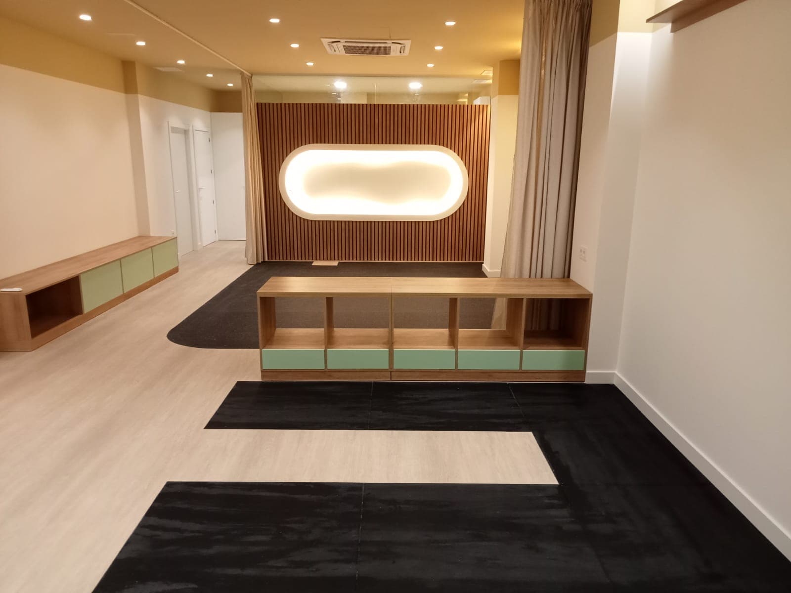 Sala con paredes y techo pintados en blanco y tonos arena, panelado de lama de madera y mobiliario a medida, acabada por Dunamis
