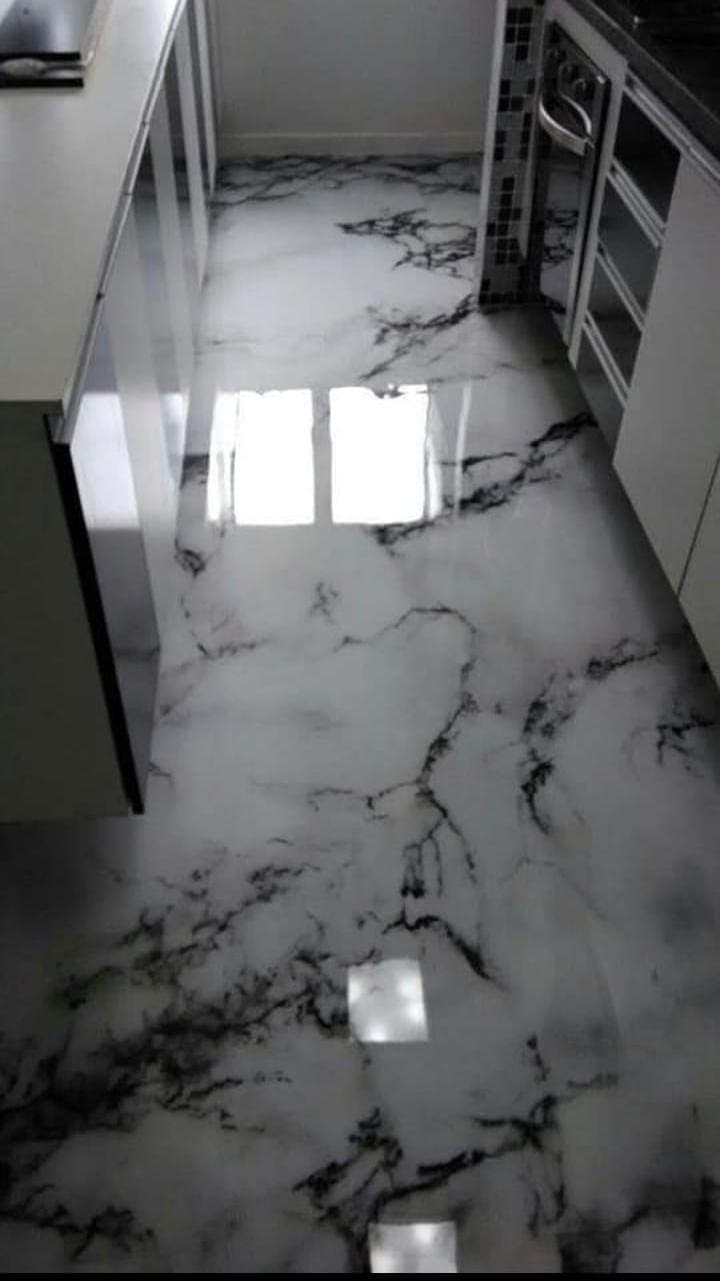 Suelo continuo de resina con veteado efecto mármol blanco en el paso a una cocina