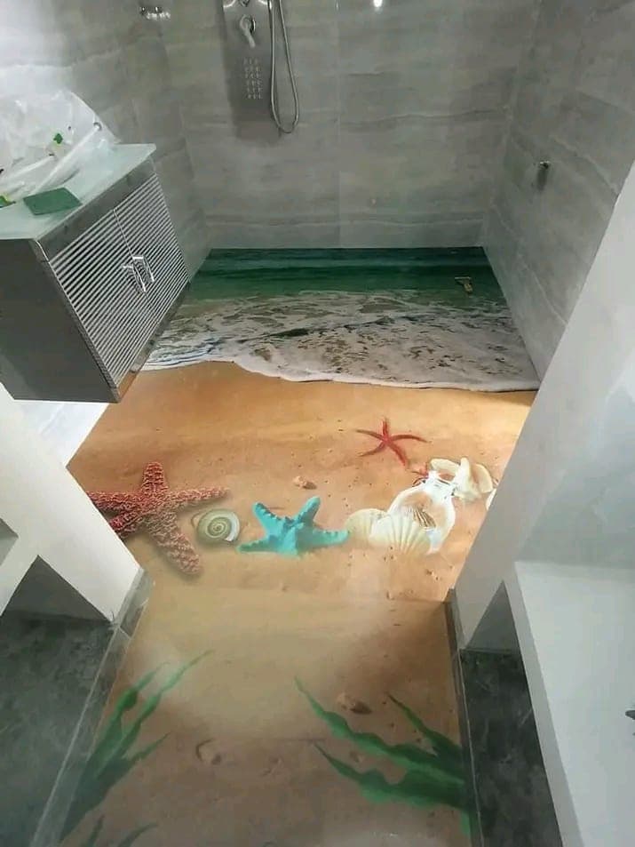 Baño con ducha y suelo continuo de resina con motivo de playa, estrellas de mar y conchas