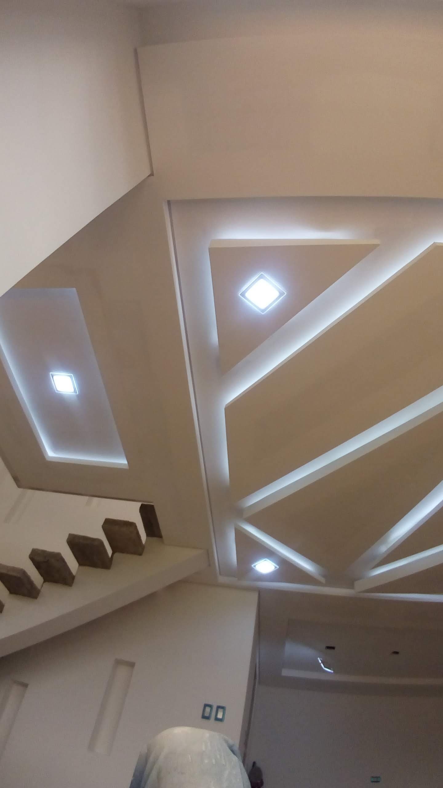 Techo de pladur con nervios geométricos iluminados sobre el hueco de una escalera