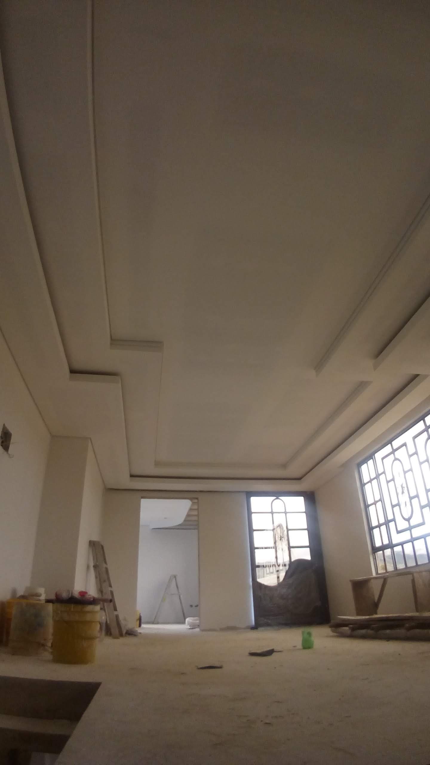 Salón en obra con falso techo de pladur escalonado en el perímetro y grandes ventanales